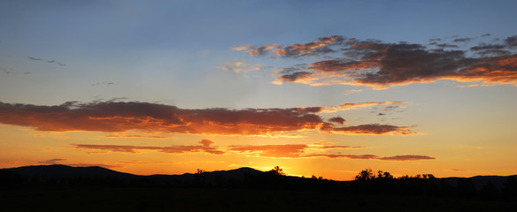 Summer orange sunset with beautiful clouds panorama