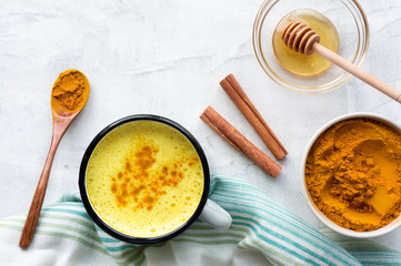 Turmeric latte, cooking Golden Milk with honey and cinnamon. Concrete background. Top 
