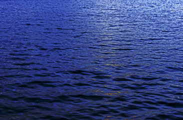 Surface of water with waves background texture, clear blue water in a lakesea with a wave, dark blue sea wave close up, azure water, glare of light on the water