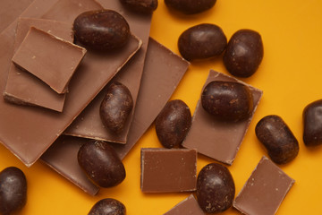 Chocolate Bar and Chocolate Pieces over Yellow Background. Sweet Dessert. top view.