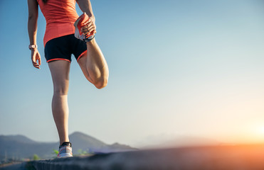 An asian woman athletic is jogging on the concrete road, she is warming her body and tideten her tying her shoes tightly fitting before workout.