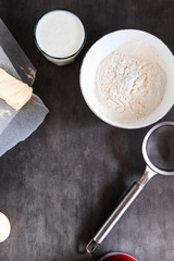 Baking ingredients, preparing dough on dark background from above. Copy space, vertical