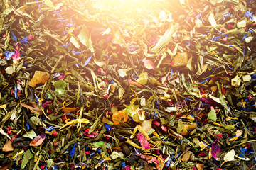Texture of green tea with dried petals of blue flowers, calendula, cornflower. Food background. Organic healthy herbal leaves, detox tea.