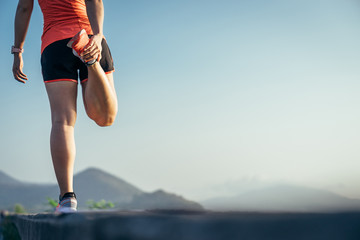 An asian woman athletic is jogging on the concrete road, she is warming her body and tideten her tying her shoes tightly fitting before workout.