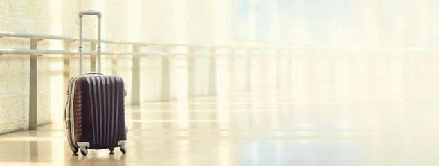 Packed travel suitcase, airport. Summer holiday and vacation concept. Traveler baggage, brown luggage in empty hall interior. Copy space. Banner