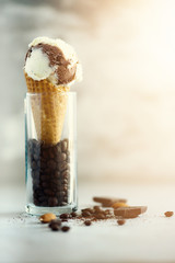 Chocolate, vanilla and coffee ice cream in waffle cone with coffee beans on grey stone background. Summer food concept, copy space. Healthy gluten free ice-cream