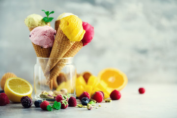 Colorful ice cream balls in waffle cones with different flavors - mango, lime, mint, pistachio,...