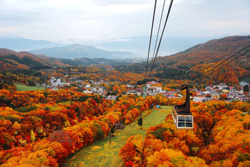 Aerial view of a scenic cable car flying over the beautiful autumn valley of Zao, a popular resort...