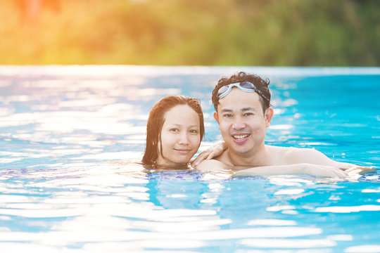 Young asian couple relaxing in swimming pool