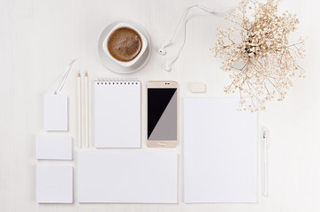 Modern minimalistic elegant wominihe work space with white blank stationery, coffee, dried white flowers, phone on white wooden board, top view.