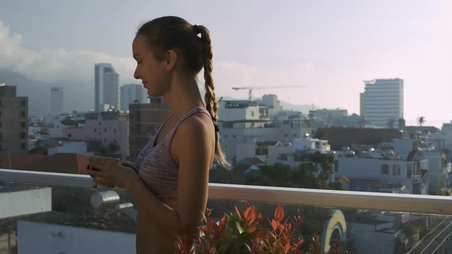 Girl Drinks Coffee on Roof Terrace against City