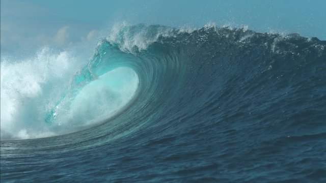 SLOW MOTION CLOSE UP: Breathtaking turquoise barrel wave crashes on a perfect summer day at the sea. Beautiful glistening tube wave crashes in the middle of the breathtaking ocean. Powerful water rush