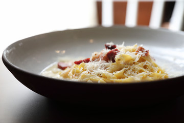 spaghetti carbonara white sauce with bacon on wood background in restaurant
