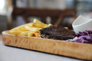 Beef cutlet for steak with fires and vegetables on wood background
