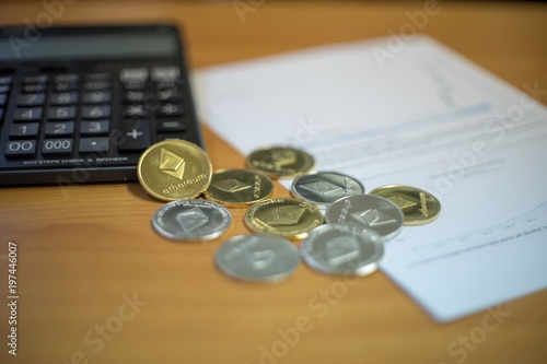 Gold And Silver Ethereum Coins On Brown Wooden Table With Calculator Gold And Silver Ethereum Coins On Brown Wooden Table With Calculator Increasing Graph The Paper Concept Of Price Increase Cryptocurrency