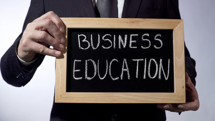 Business education written on blackboard, businessman holds sign, future