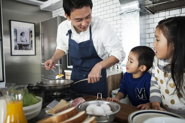 お父さんが目玉焼きを作ってくれました。美味しそうです。息子と娘が見守っています。