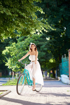 Vertical full length portrait of a beautiful young woman cycling in the park on a sunny summer day smiling happily enjoyment expressive recreational active sporty travelling nature.