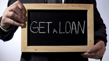 Get a loan written on blackboard, businessman holding sign, business concept