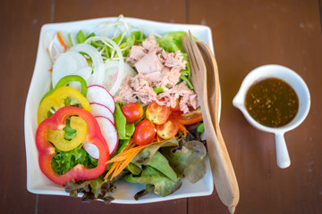 Fresh mixed vegetable salad in a bowl on a wood background.