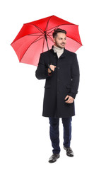 Young man in warm coat with red umbrella on white background