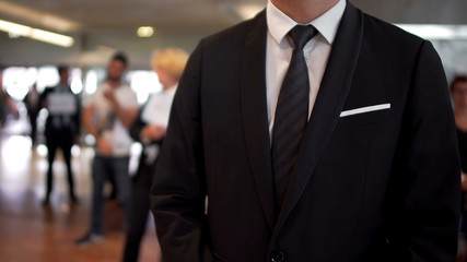 Man in business suit waiting for arrivals in airport hall, travel agent, tourism