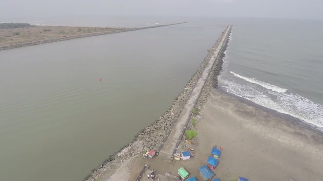 A boardwalk located in Kerala, India with a beautiful aerial view of the sea and waves hitting the sides of the boardwalk.