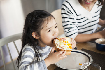 大きな口を開けて、トーストを食べる女の子。