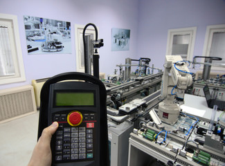 Industry 4.0 concept. Man is holding tablet to control smart factory manufacturing line which is equipped with sensors and robotic arm. industrial automation line.