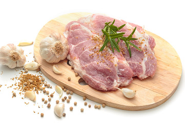 Raw pork meat steaks with spices on wooden chopping board.