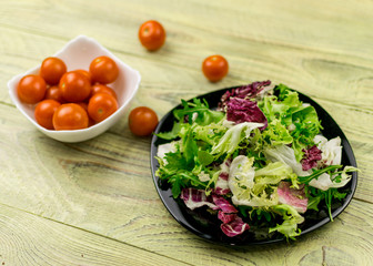 Vegetarian salad of fresh vegetables and tomatoes cherry plate on a wooden background.