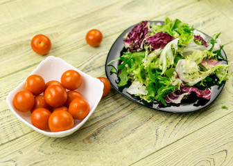 Vegetarian salad of fresh vegetables and tomatoes cherry plate on a wooden background.