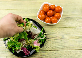 Vegetarian salad of fresh vegetables and tomatoes cherry plate on a wooden background.