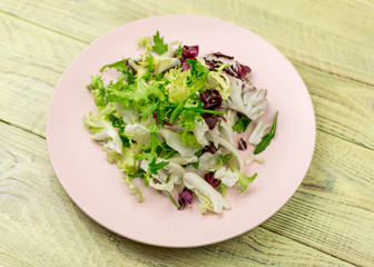 Vegetarian salad of fresh vegetables on a plate on a wooden background.