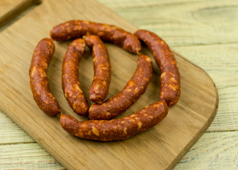 Smoked natural sausages   on a wooden surface.