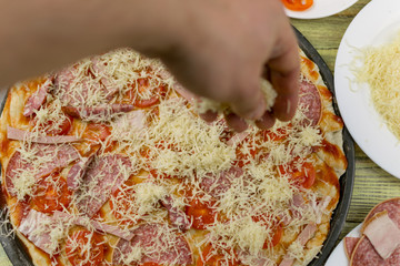 Obraz na płótnie Canvas Fresh original Italian raw pizza, dough preparation in traditional style. Sprinkle with grated cheese.