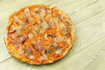 Freshly prepared homemade pizza on a wooden background.