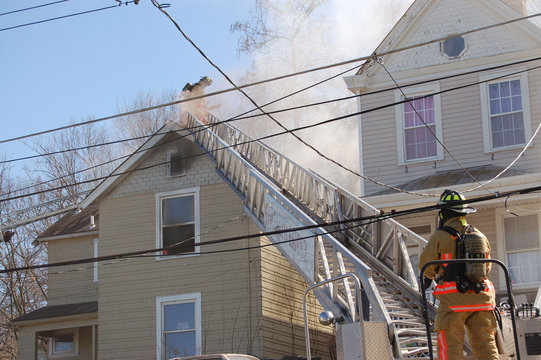 firemen fighting a roof fire on a quiet neighborhood street