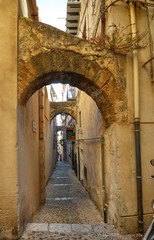 Fototapeta na wymiar Cefalù, Italy, Sicily August 16 2015. The alleys of cefalù that wind at the foot of the fortress behind the cathedral. Steep stairways, picturesque signs. Narrow streets, flower boxes, laundry threads