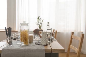 Interior view of wooden simple table with products and utensils in daylight. 
