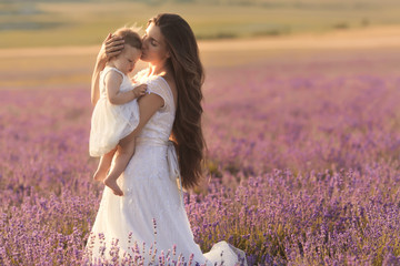 Happy beautiful mother and cute little daughter have fun in aroma lavender fields. Family holiday...