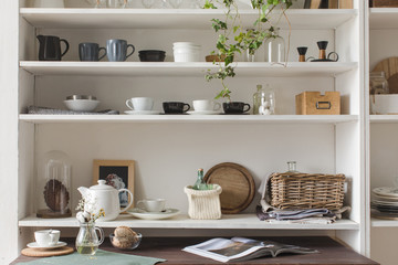 Obraz na płótnie Canvas White wooden shelves with decorative elements and elegant kitchenware. 