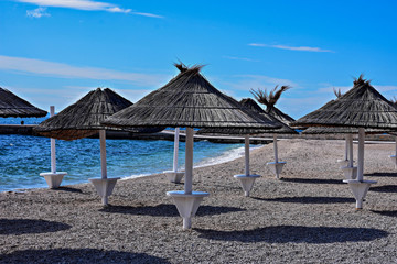 Umbrella and a bamboo sun shade in an empty paradise beach at sunny day
