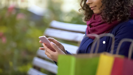 Woman watching pages on smartphone, choosing items online, mobile shopping