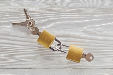 Two padlock, lock and unlock, with silvered keys on white wooden background. Estate and security...