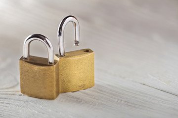 Fototapeta premium Two padlock, lock and unlock, with silvered keys on white wooden background. Estate and security concept with symbol of protection.