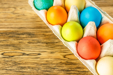 Obraz na płótnie Canvas Bright Easter eggs in a special stand. Happy Easter. Close-up, blurred background. Wooden background, place for text. The view from the top.
