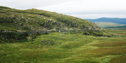 Green hills and the road on the hillside. A scenic view of a Kerry Mountains and surrounding areas in County Kerry. Aged effect. Landscape along the Ring of Kerry. Ireland. Wide photo for web page.