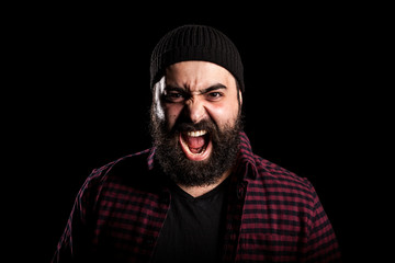 Bearded man screaming in anger on black background in studio photo