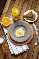 English Breakfast: fried egg, juice, cherry tomatoes, lettuce, grain bread, sauce, top view.
